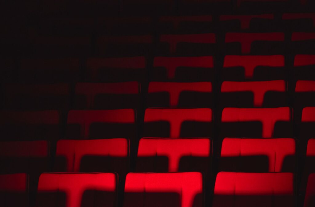 Dramatic spotlight illuminating an empty stage with deep red velvet theatre seats in a historic performance hall, evoking anticipation and a sense of classic nostalgia.