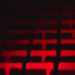 Dramatic spotlight illuminating an empty stage with deep red velvet theatre seats in a historic performance hall, evoking anticipation and a sense of classic nostalgia.